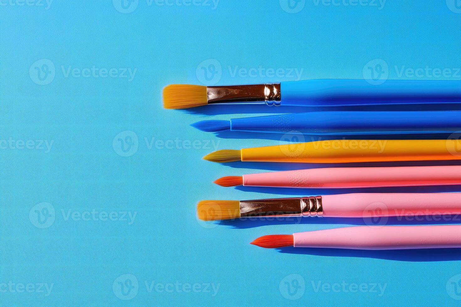 Colorful paint brushes forming a line on blue background photo