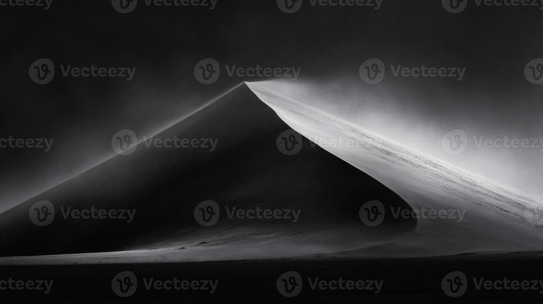 Sand dune emerging from darkness with blowing sand in black and white photo