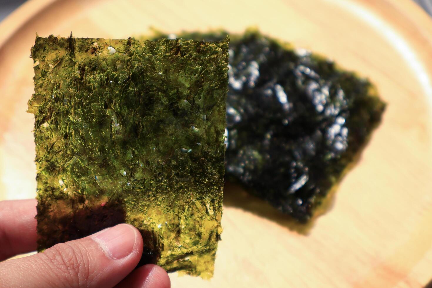 Hand holding a type of roasted seaweed sheet. photo