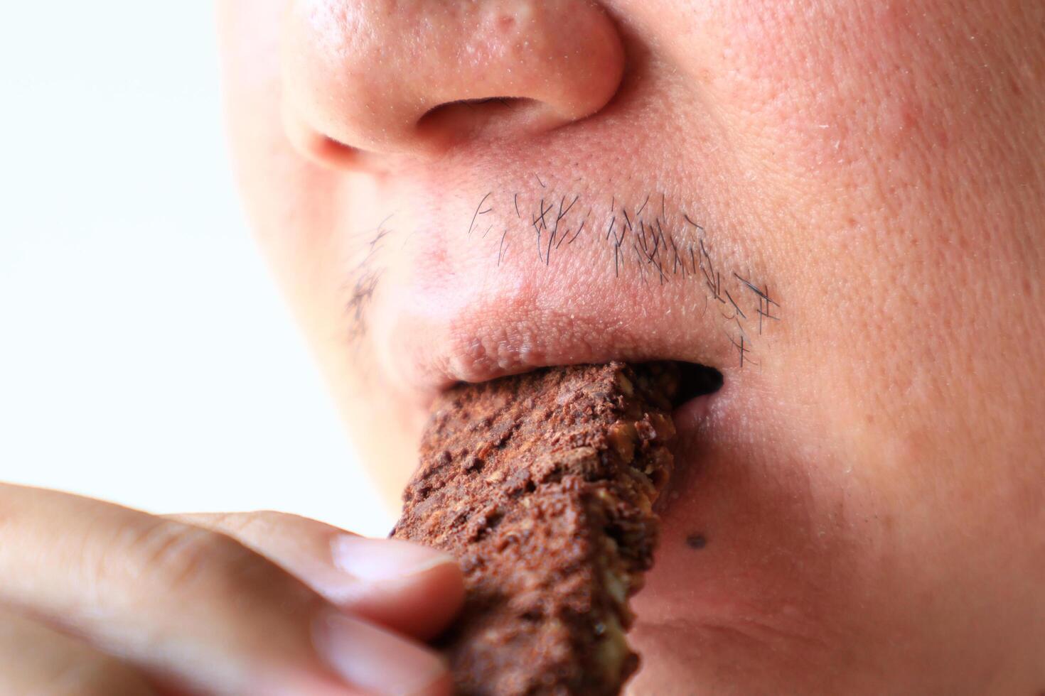 Young Asian man eating healthy granola bar chocolate or cocoa flavor. wellness concept photo