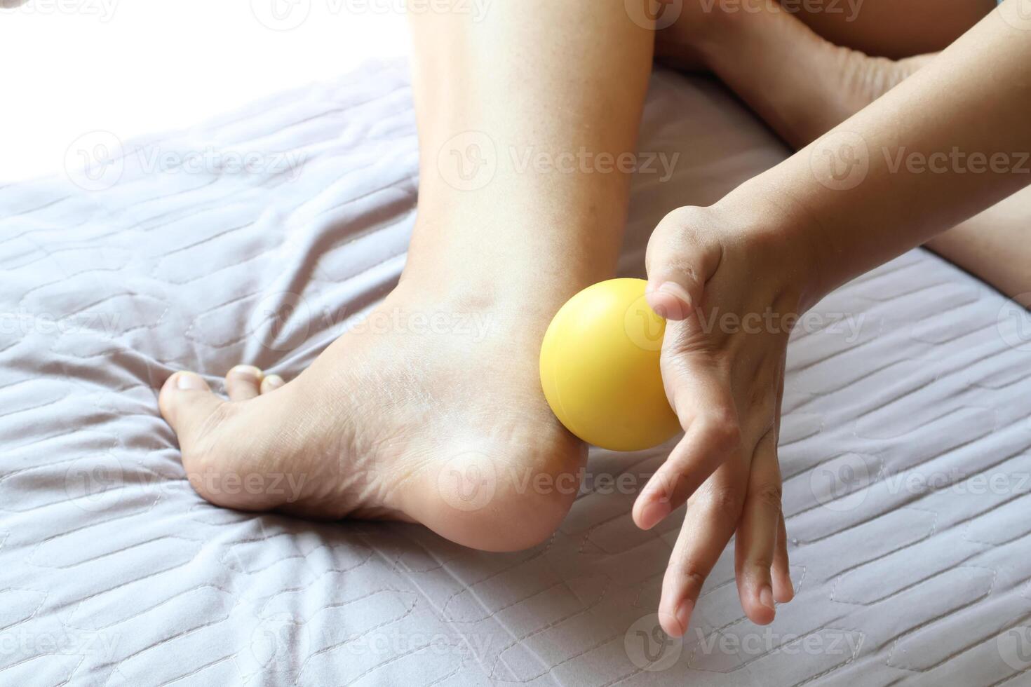 Achilles tendonitis. Use a massage ball on your ankle or foot to relieve pain. foot wellness concept photo