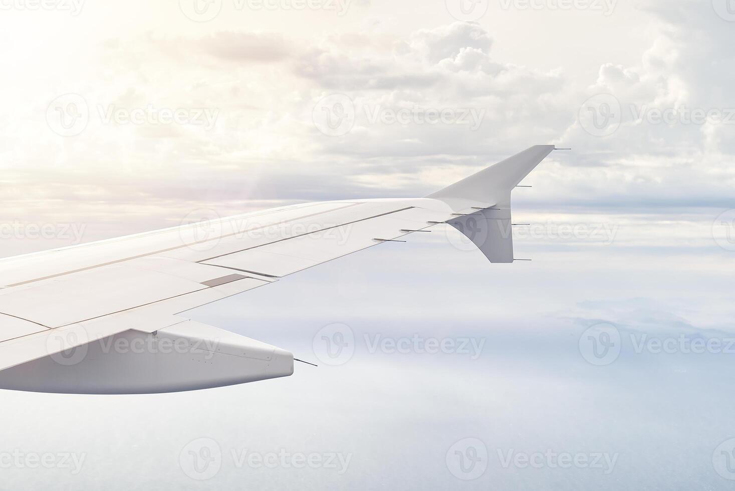 Airplain wing view thrue window in the sky. Clouds and sky as seen through porthole of an aircraft with airplane's wing photo