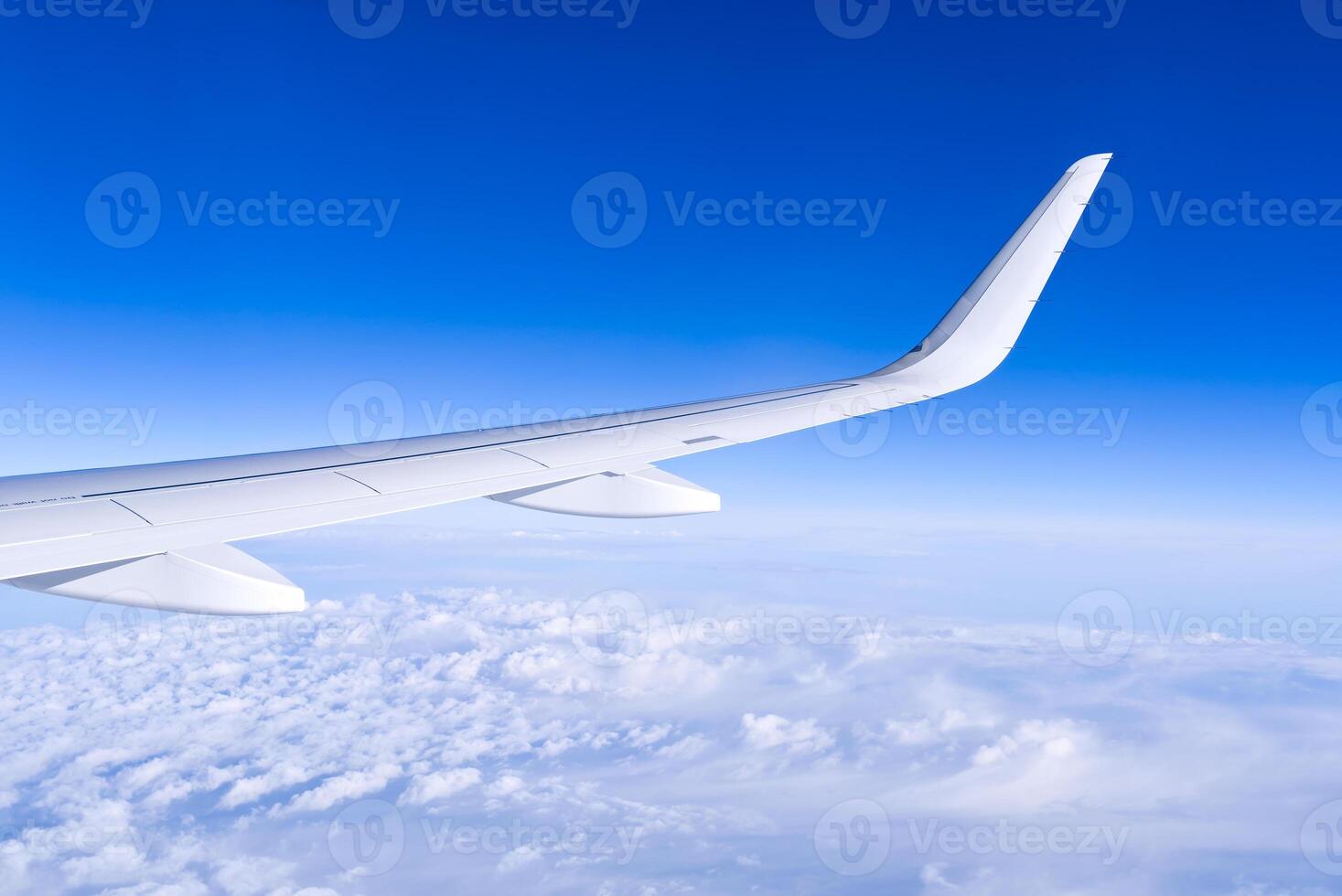 Airplain wing view thrue window in the sky. Clouds and sky as seen through porthole of an aircraft with airplane's wing photo