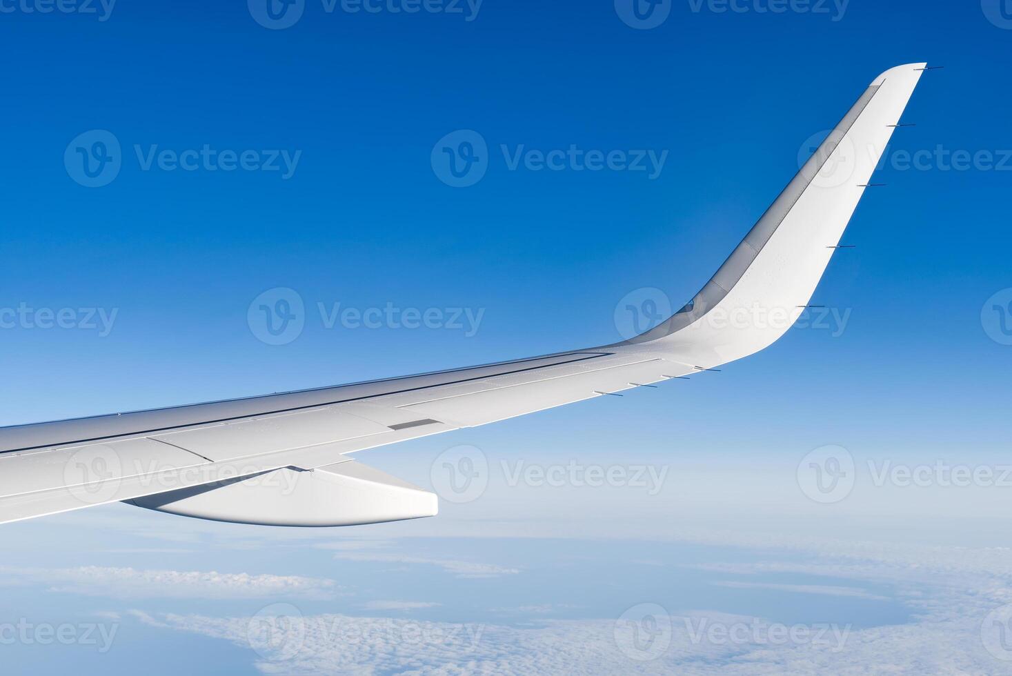 Airplain wing view thrue window in the sky. Clouds and sky as seen through porthole of an aircraft with airplane's wing photo