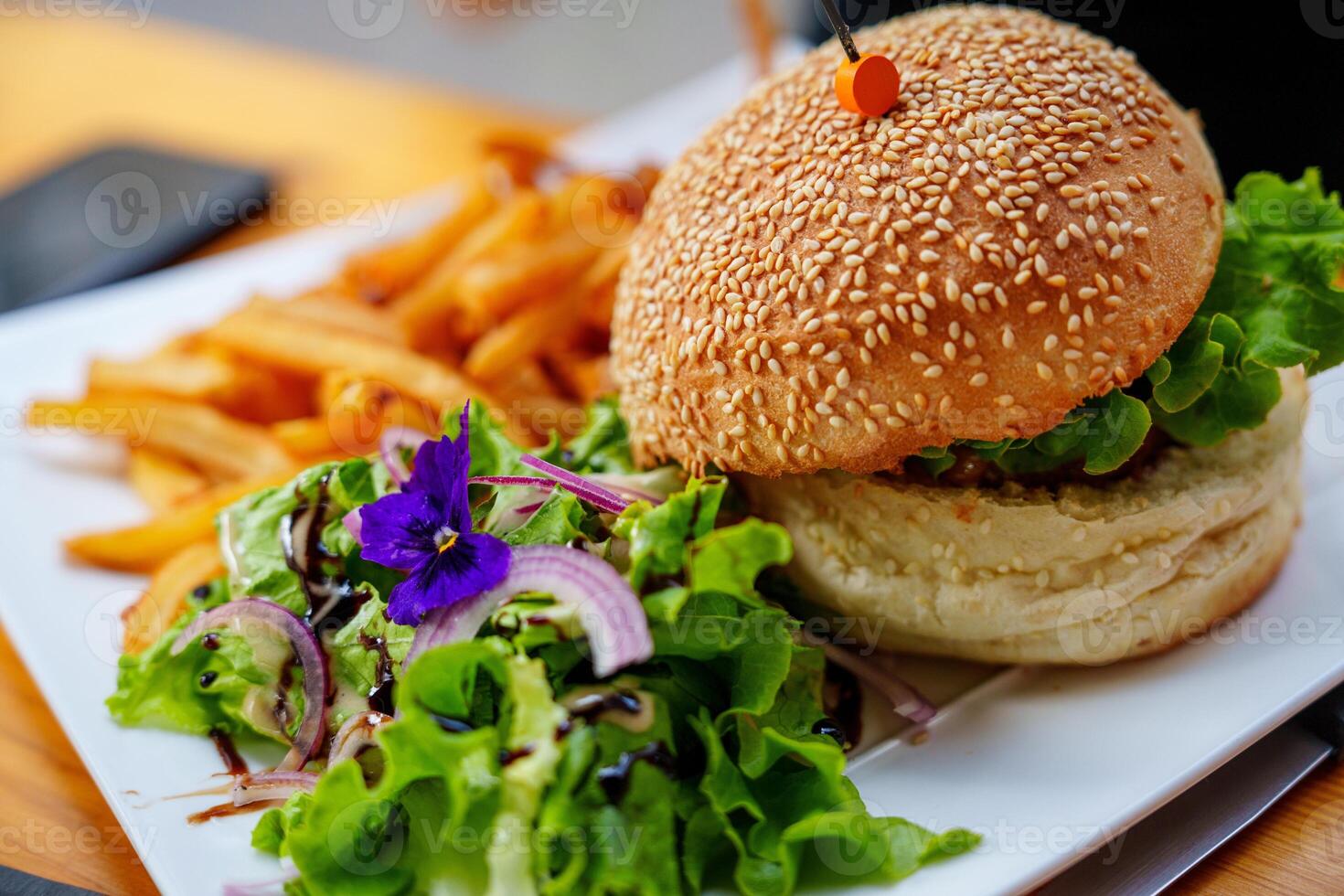 Delicious Gourmet Burger with Fresh Toppings and Crispy Golden Fries Served on a Beautiful Plate photo