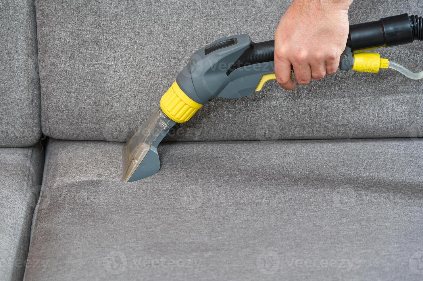 Sofa chemical cleaning with professionally extraction method. Wet textile sofa cleaning. home cleaning service. cleaning sofa with washing suction cleaner closeup. photo