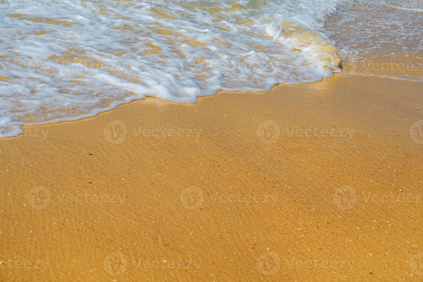 The image displays gentle waves rolling onto a sandy beach. The vibrant blue water meets warm golden sand, creating a peaceful coastal scene that invites relaxation and tranquility. photo