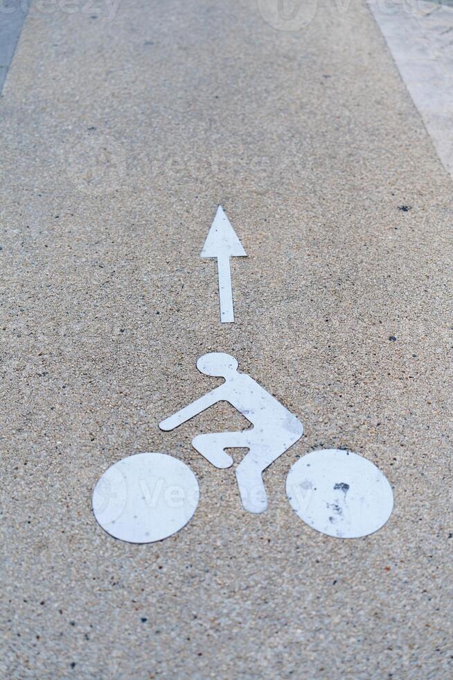 The image displays a white bicycle lane sign on gray concrete. This sign marks the designated area for cyclists, promoting safety and encouraging proper lane usage for all road users. photo