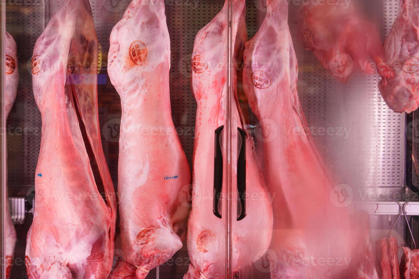 Fresh lamb carcasses hanging in a cold storage room of a butcher shop. photo