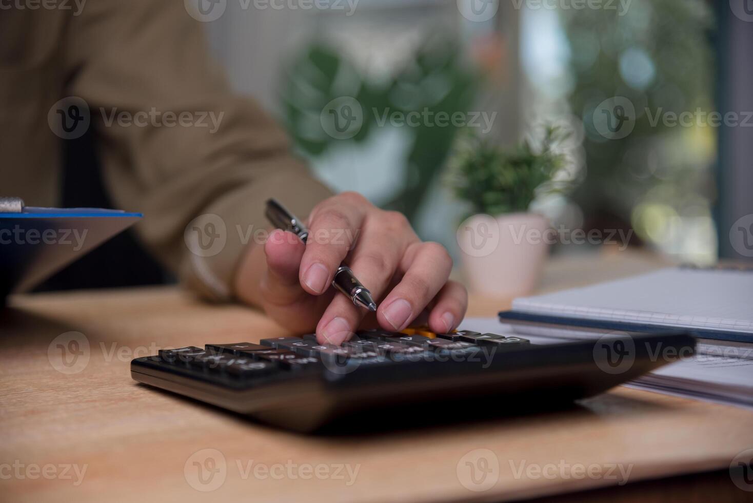 A person is using a calculator on a desk photo