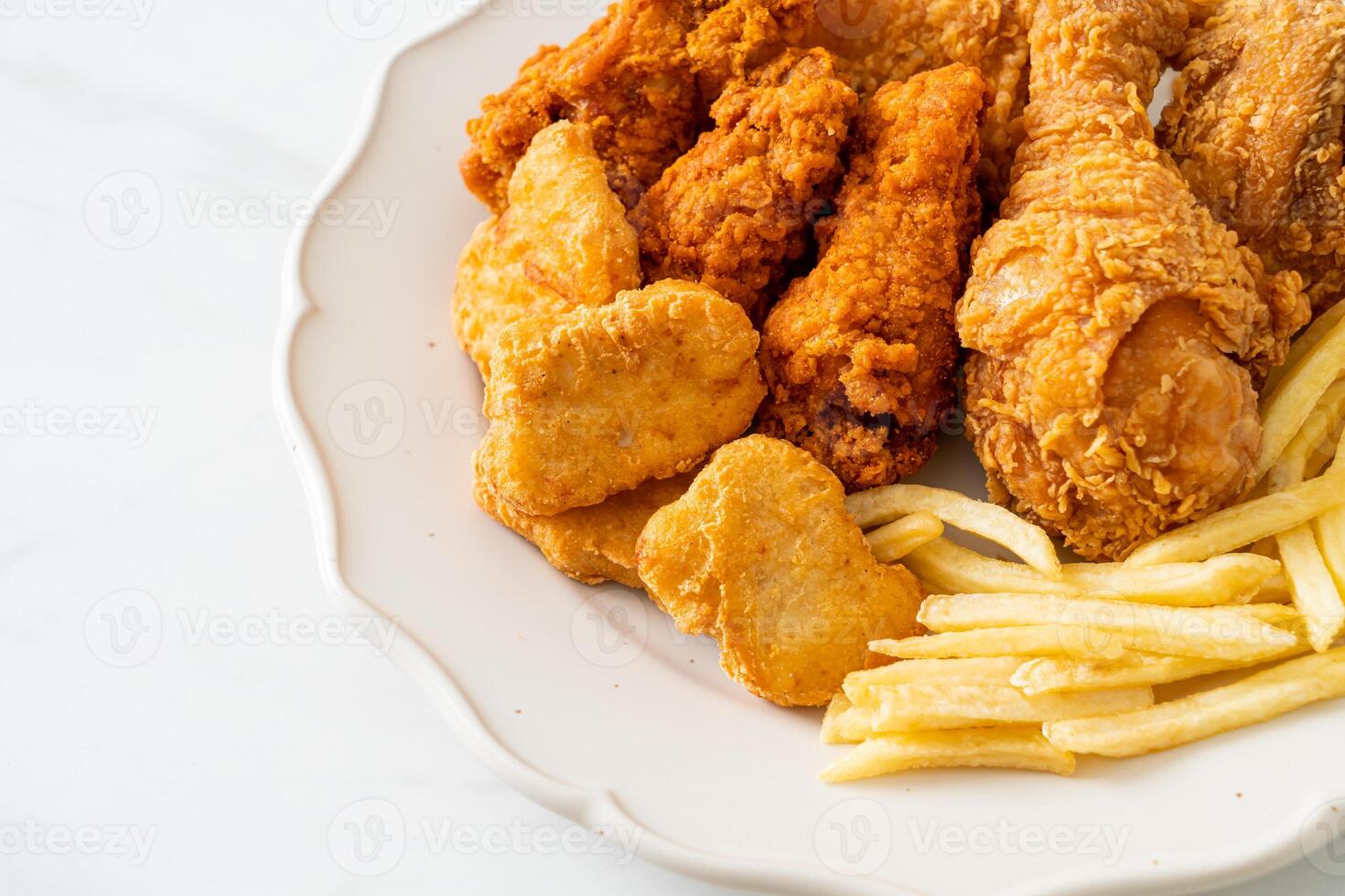 fried crispy chicken with french fries and nuggets on white plate photo
