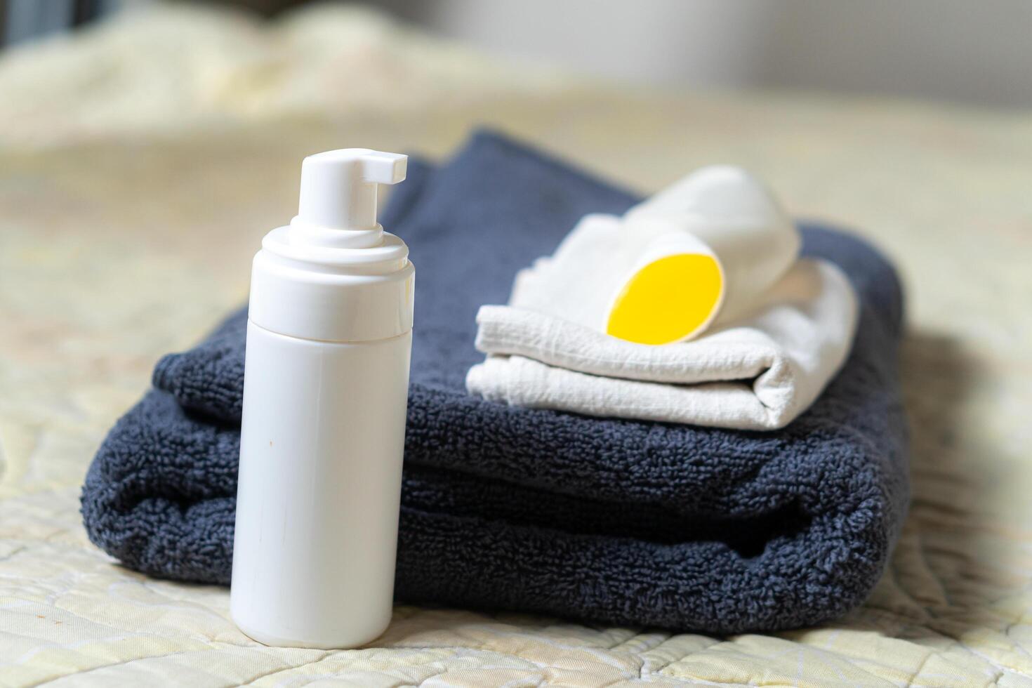 A bottle of deodorant and a towel on a bed photo