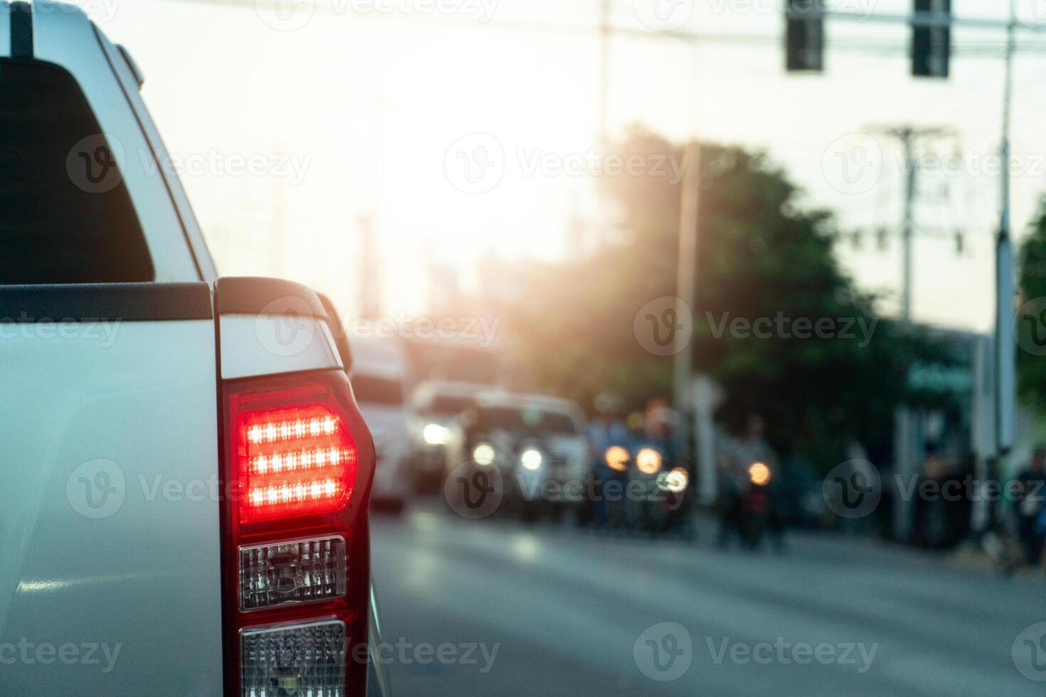 Rear side view of pickup car. Stop and turn on brake light on asphalt road. Stopped at a traffic light and there was a car crossing the road. photo