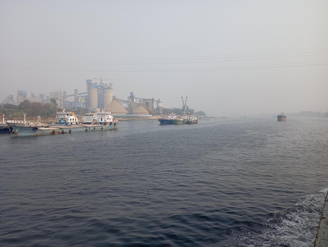 a river with boats on it and a factory in the background photo