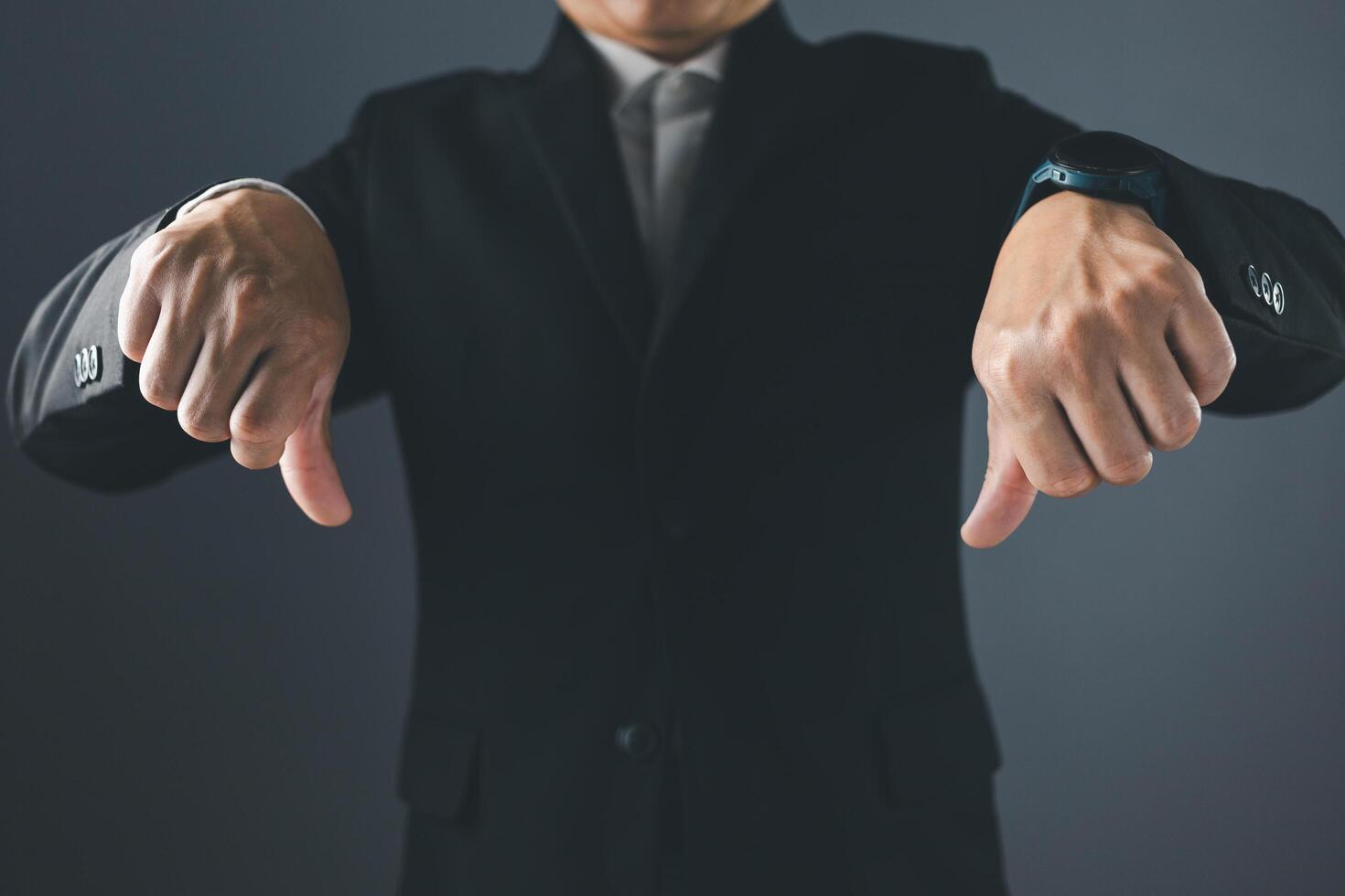 A man in a suit stands with his thumbs down, showing dissatisfaction, bad service, bad things, bad feelings photo