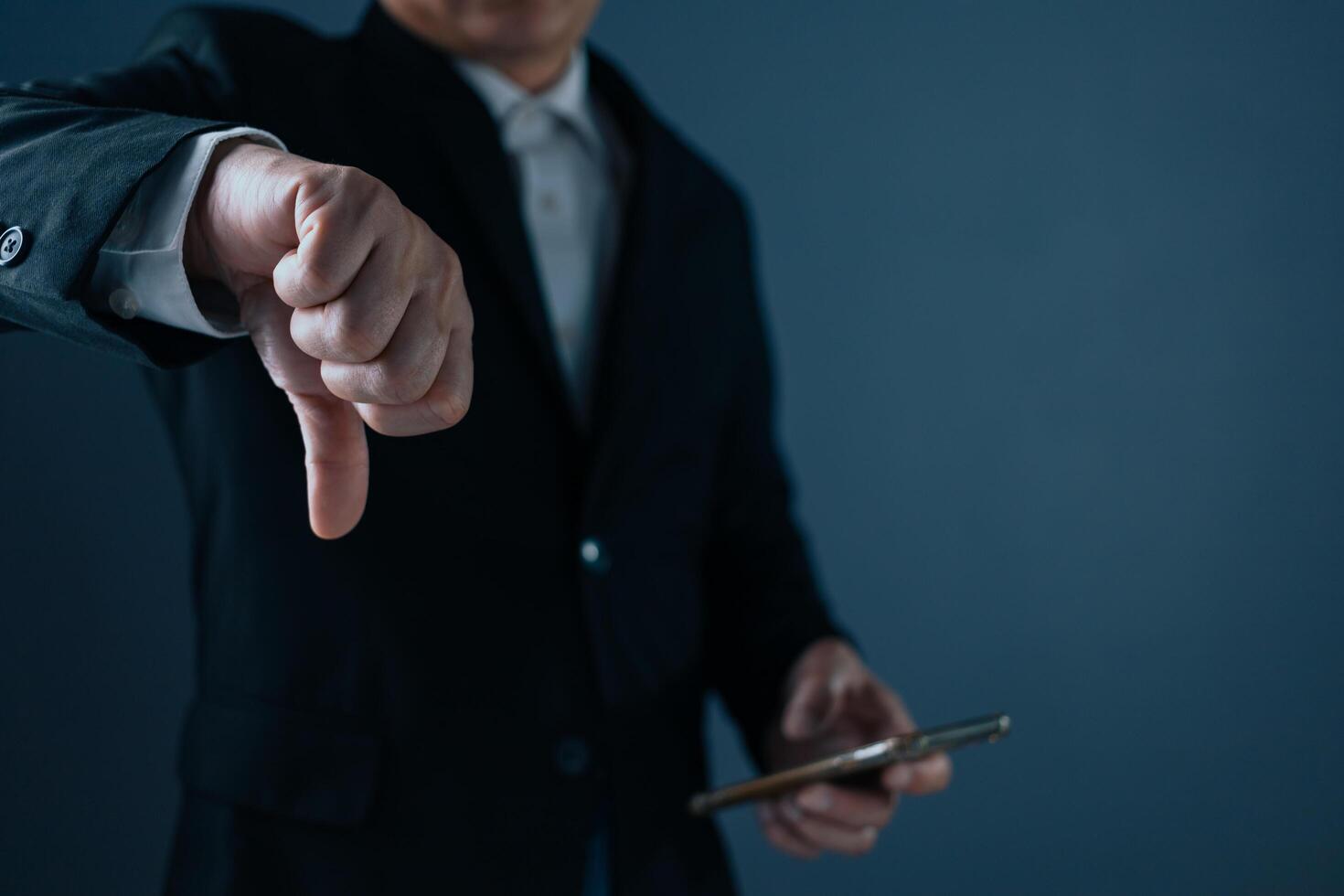 A man in a suit stands with his thumbs down, showing dissatisfaction, bad service, bad things, bad feelings. photo