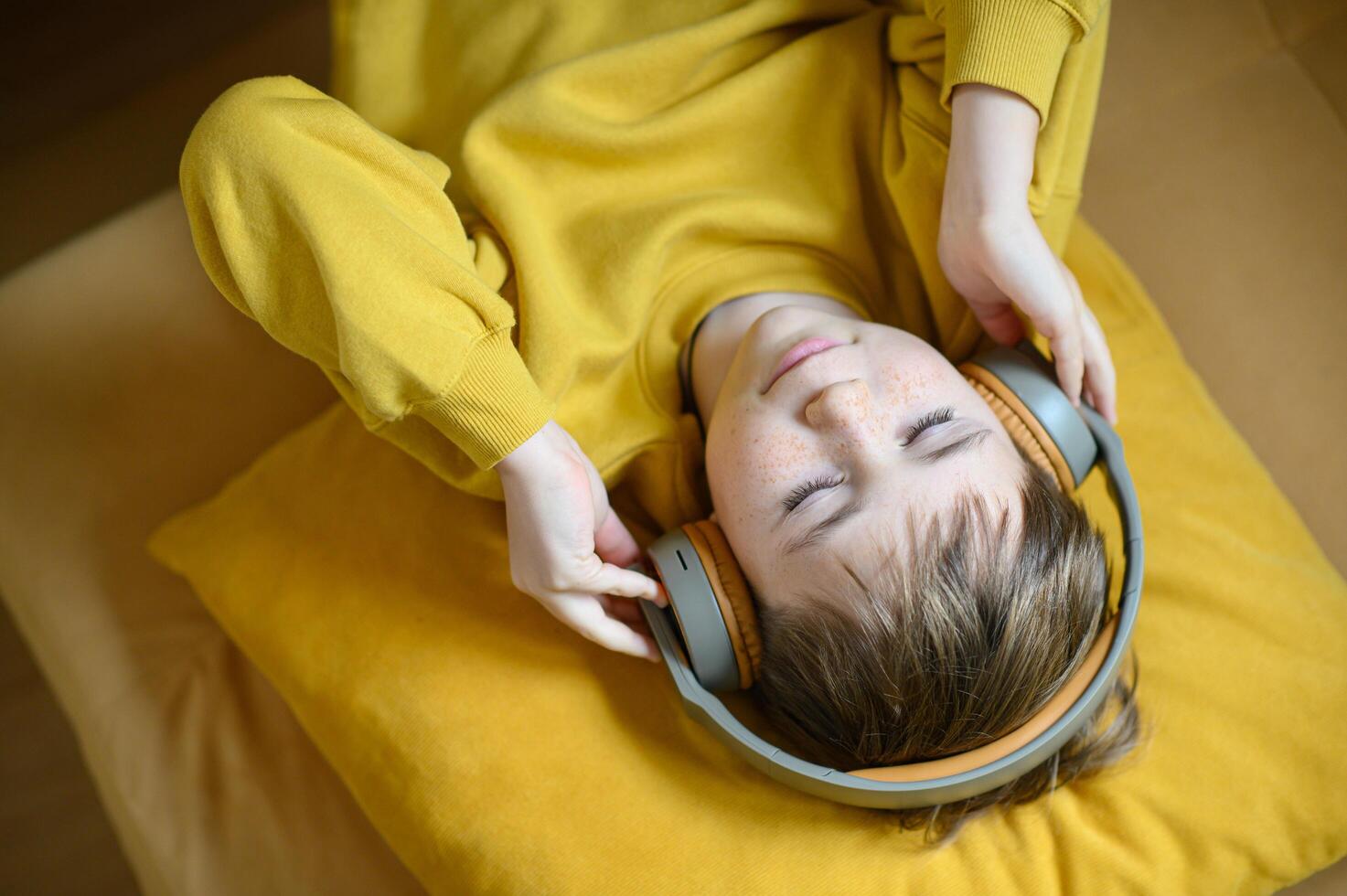 boy is listening music and enjoy it in a yellow sweater photo