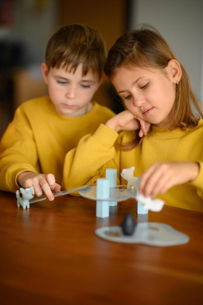 The siblings laugh as they take turns playing a colorful board game at home. photo