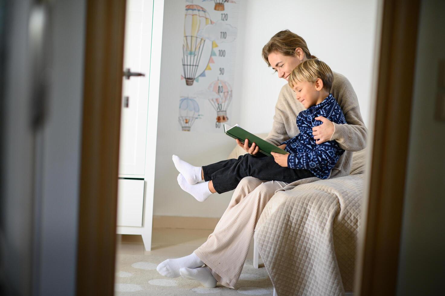 The mother and son share a quiet moment on the bed, enjoying a story from their book. photo