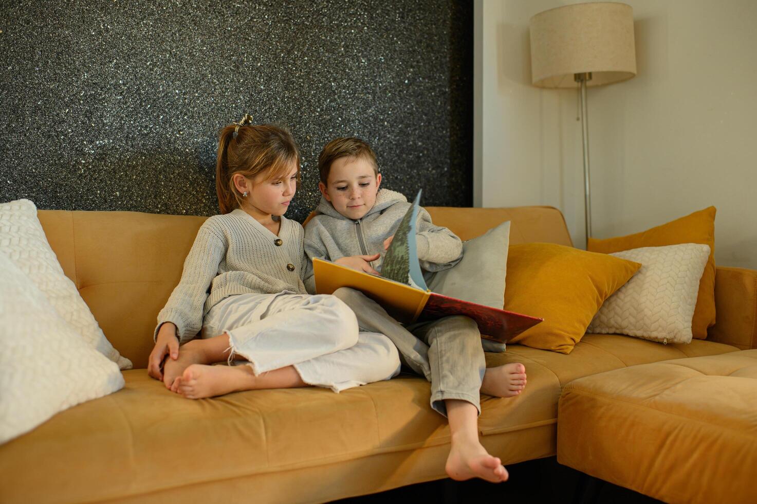 The siblings relax on the sofa, flipping through the pages of a book, enjoying a quiet moment. photo