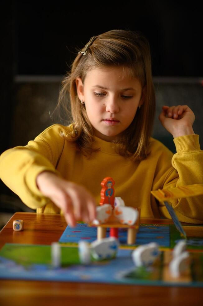 At home, a girl concentrates on her next move in a colorful board game. photo
