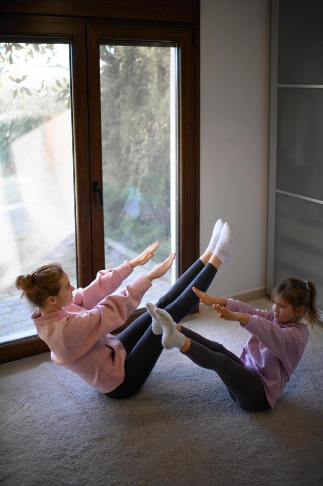 A mom and her daughter doing Pilates in their living room photo