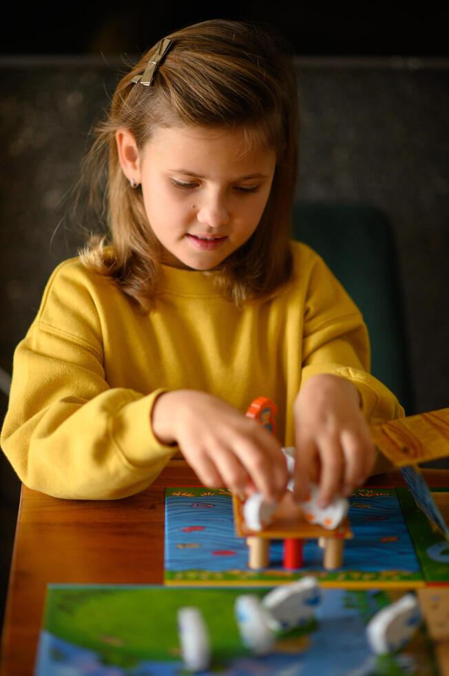 In a warm room, a girl leans over the table, enjoying a board game. photo