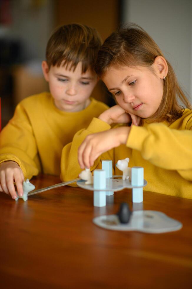A boy and girl work together on a kids board game, smiling and having fun. photo