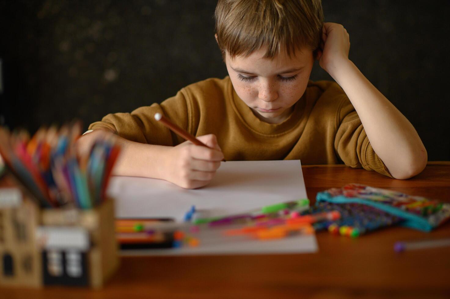 A boy sits quietly, looking at his drawing tools, pondering his next sketch. photo