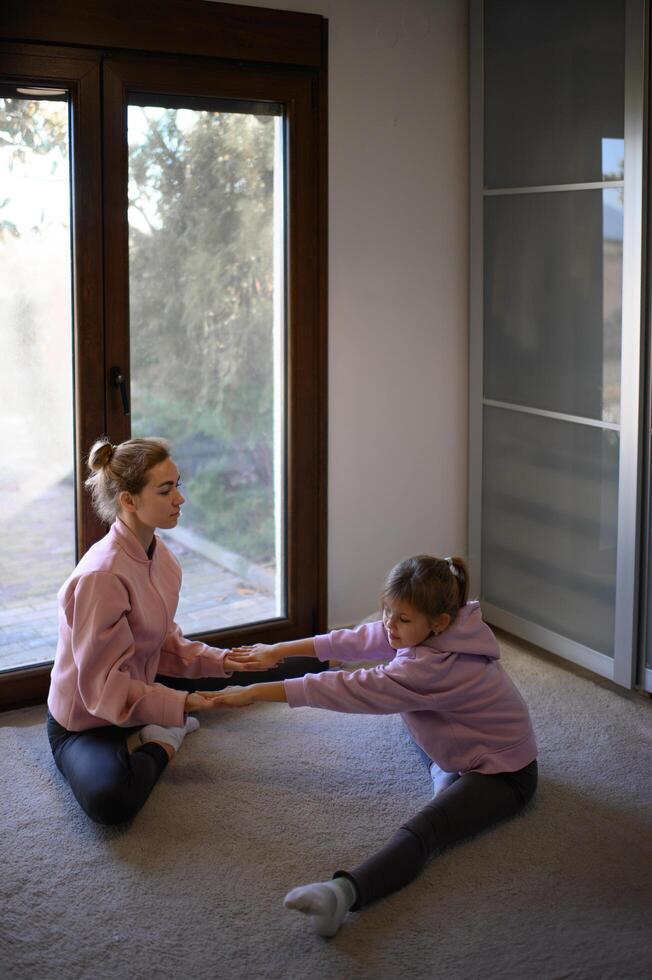 A mother and daughter stretching together with resistance bands, improving flexibility at home. photo