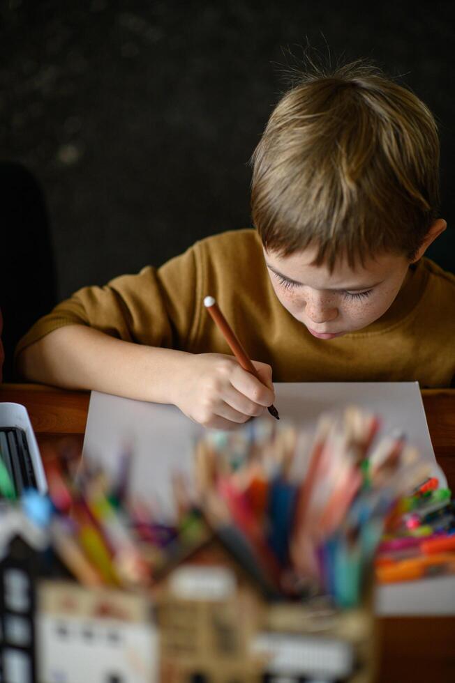 A child with a blank page and markers sits, brainstorming his next artwork. photo