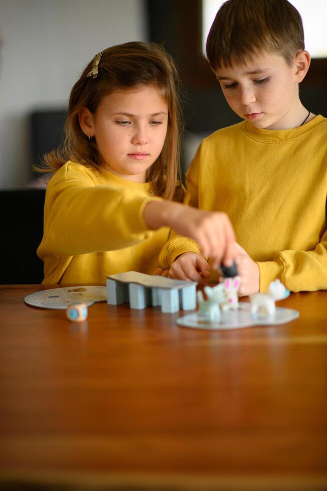 The siblings challenge each other in a friendly game, sitting at the table at home photo