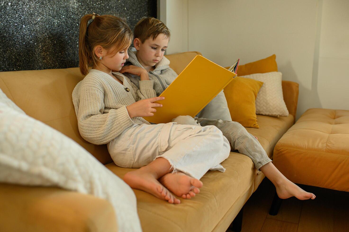 A boy and girl cuddle up on the couch, each holding a book and enjoying the read. photo