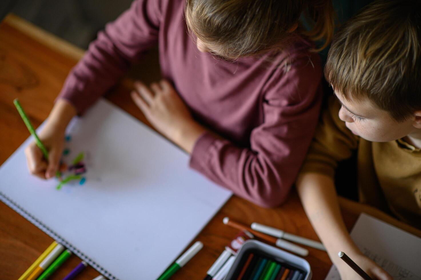 A boy and girl share a table filled with pencils and markers, brainstorming their next artwork. photo
