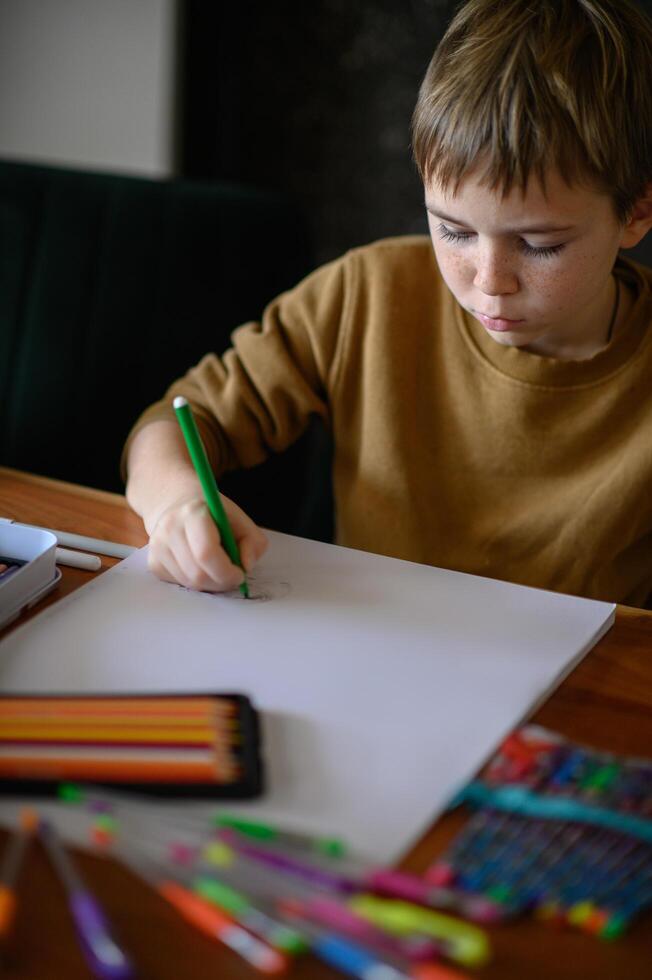 A young boy, with markers in hand, thinks deeply about his next drawing idea. photo