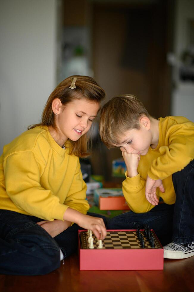 Children in yellow sweaters share a moment of laughter while deciding their chess strategies. photo