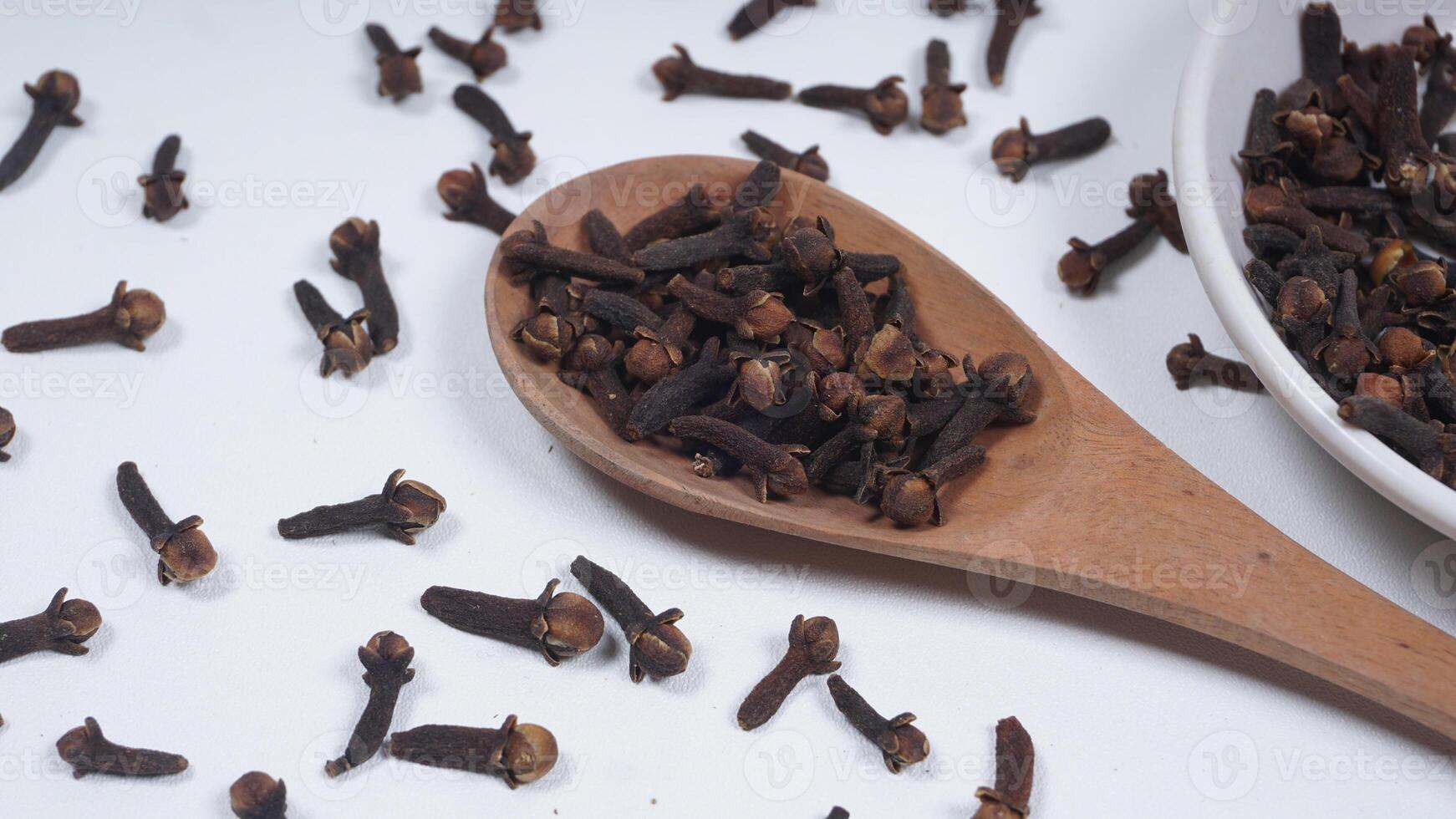 Cloves Spice on Wooden Spoon and Bowl Isolated on White Background photo