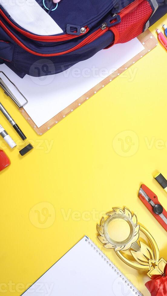 School Stationery, Notebook, Backpack, and Wooden Clip Board with Copy Space Area on Yellow Background photo