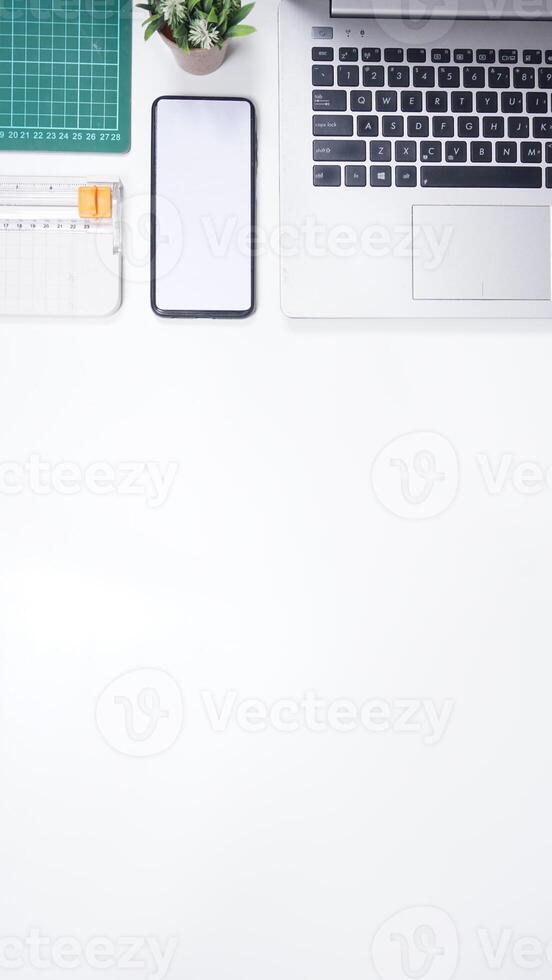 Modern Workspace with Laptop, Mobile Phone, and Work Tools on White Background photo