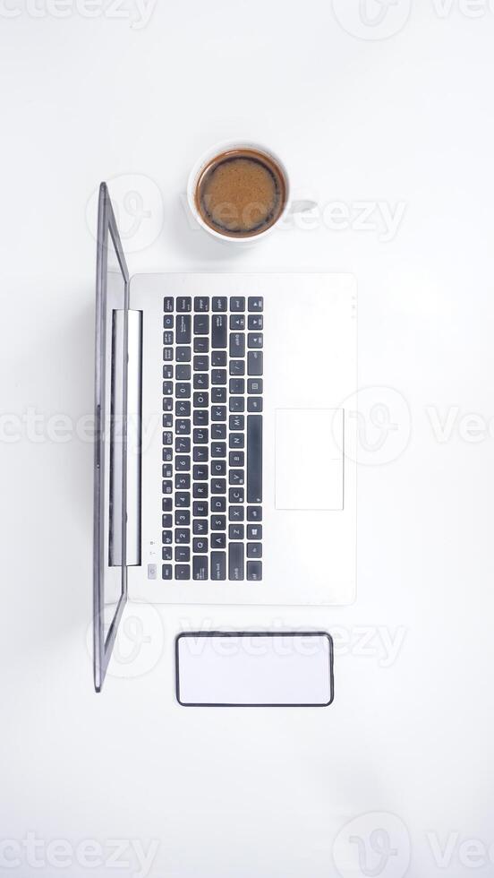 Top View of Laptop with Mobile Phone and Coffee Cup on White Background photo