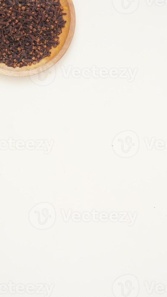 Dried Cloves on Wooden Plate on Light Background photo