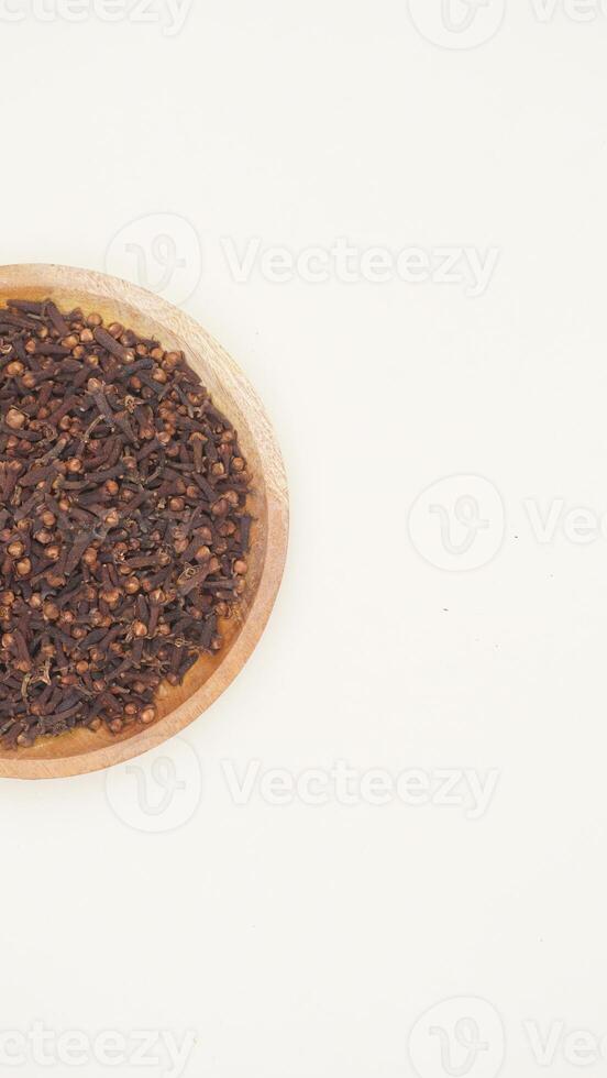 Dried Cloves Spice on Wooden Plate on Light Background with Copy Space photo
