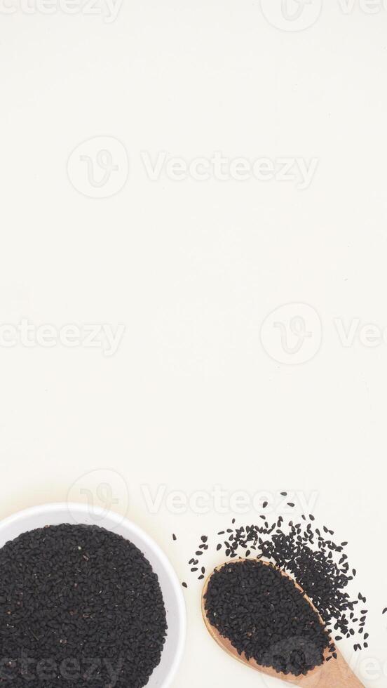 Black Cumin Spice on Plate and Wooden Spoon on Light Background photo