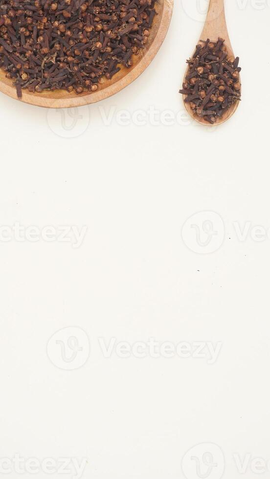 Dried Cloves Spice on Wooden Plate and Spoon on Light Background photo