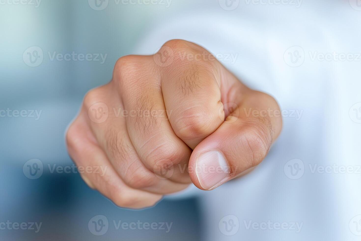 Close-up of a male hand making a fist gesture with a blurred background photo
