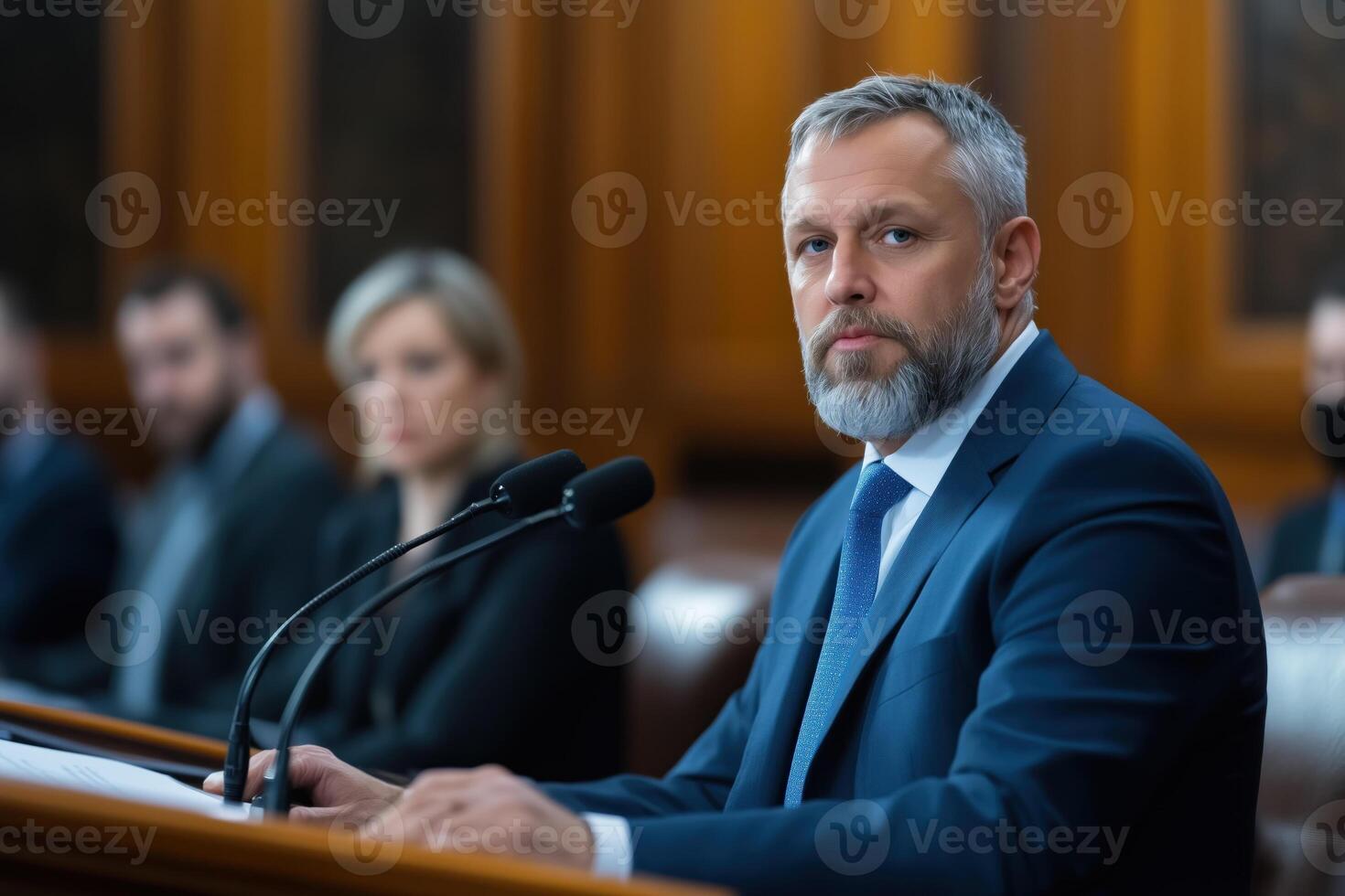 Serious mature man in blue suit making a speech in front of microphones photo