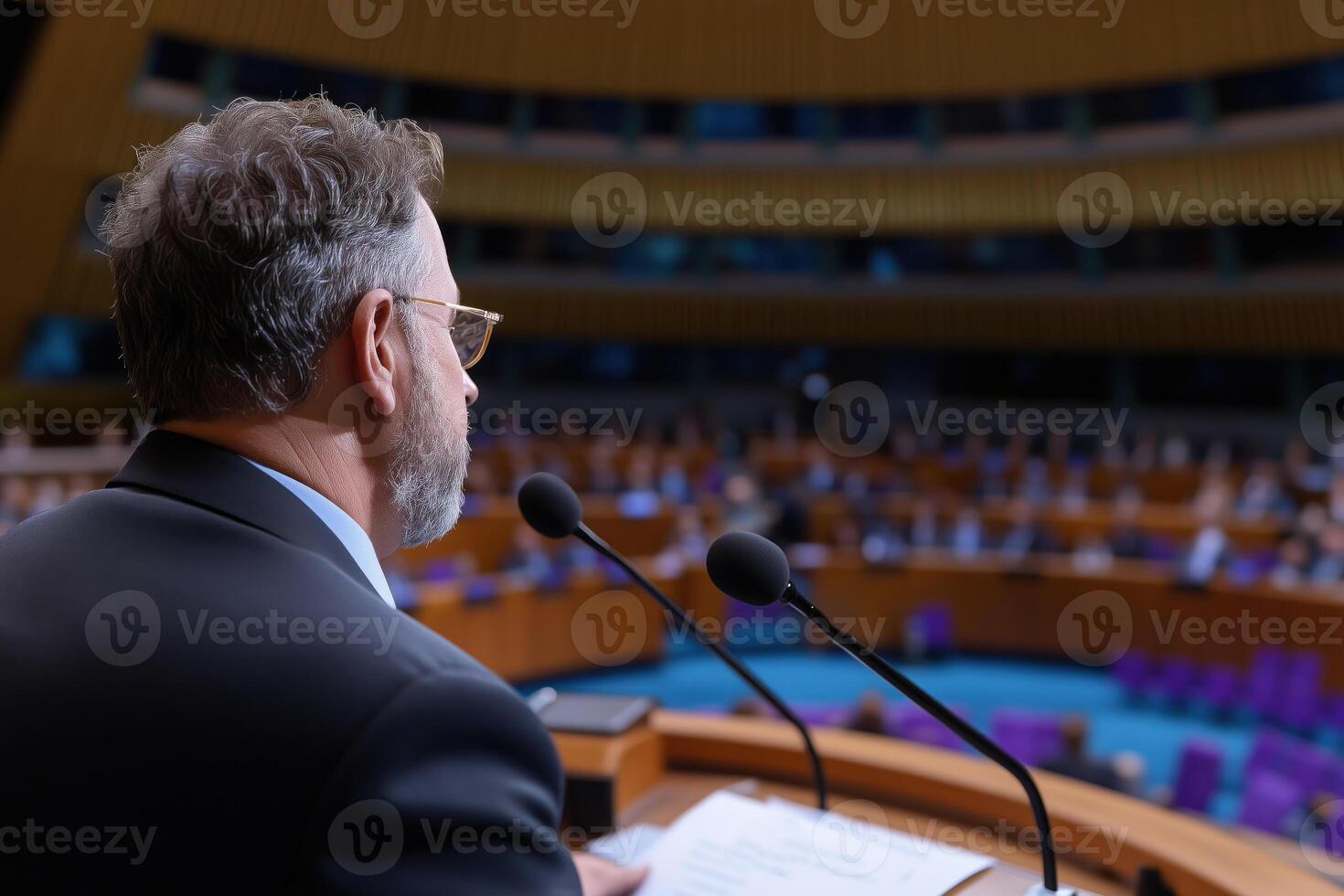 Rear view of senior man in formalwear at tribune giving speech at conference hall. photo