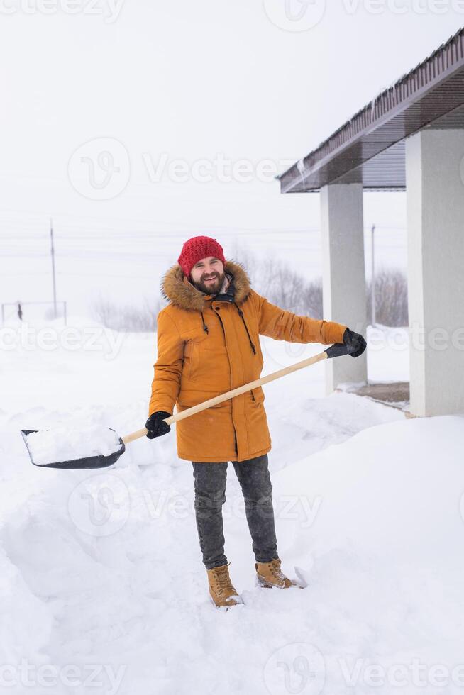 Man is clearing the snow near house and on staircases hovelling at the winter season. Winter storm and season specific photo