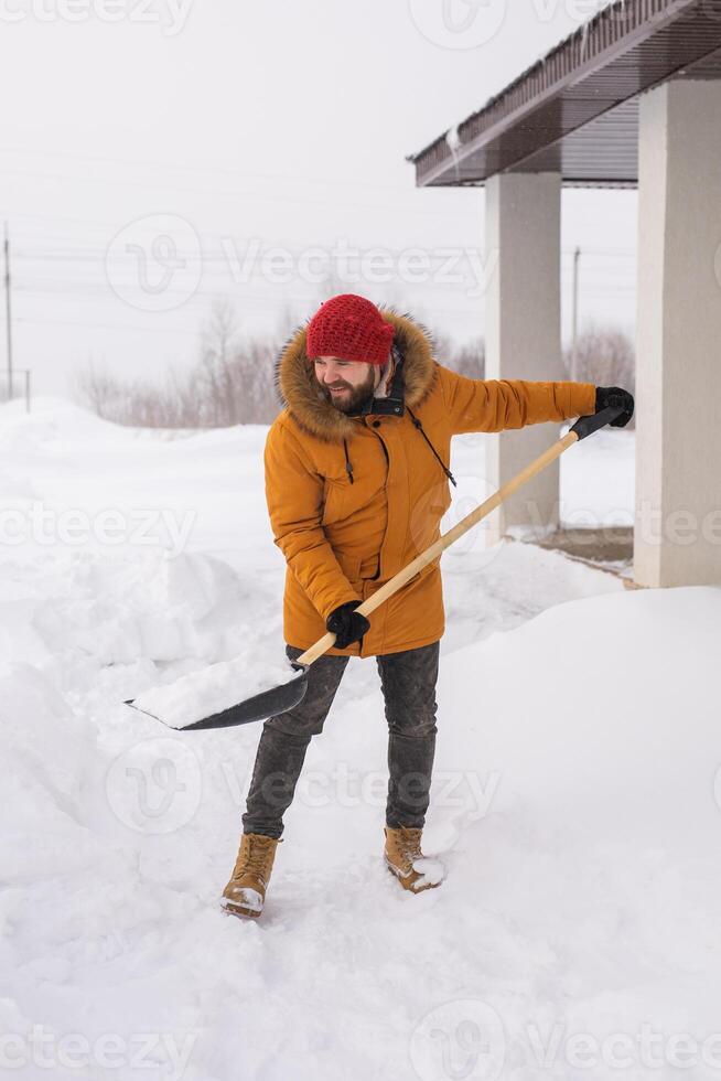 Man is clearing the snow near house and on staircases hovelling at the winter season. Winter storm and season specific photo