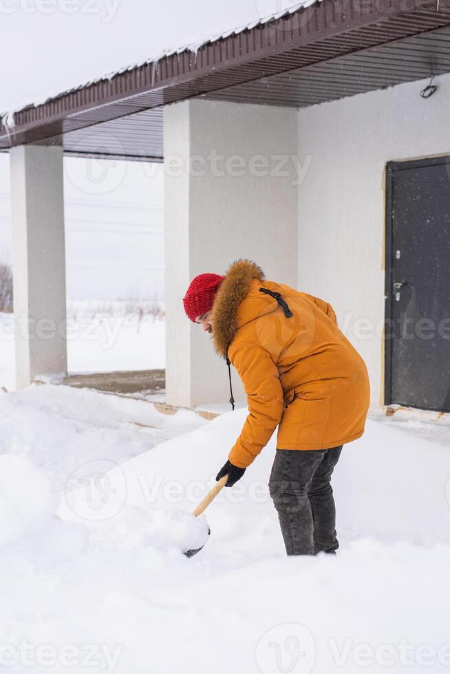 Man cleaning snow from sidewalk and using snow shovel. Winter season photo